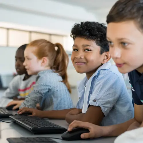 Børn der sidder i en klasse foran en computer